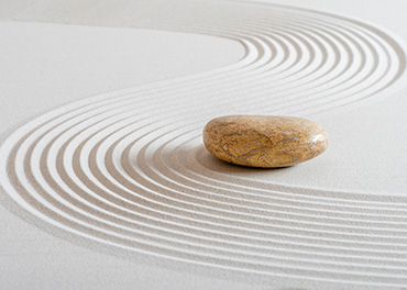 Sfeerbeeld Zen steen met stroomlijnen in zand