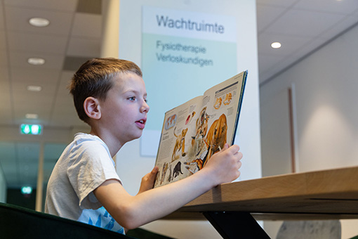 Wachtruimte Gezondheidscentrum RijswijkBuiten Fysiotherapie waarin een jongen een boek leest